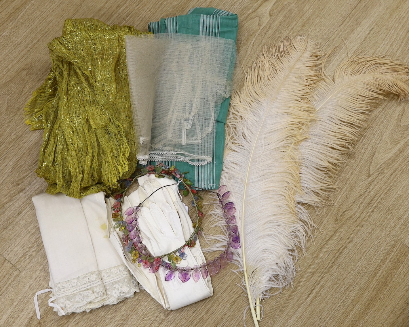 Two 1920's floral bead headdresses, a baby dress, gold fabric, two feathers and three prs of gloves
